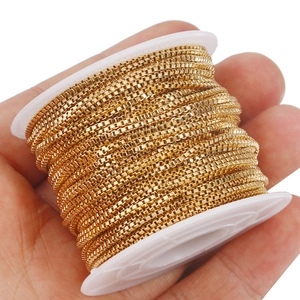 Close-up of golden stainless steel box chain roll being held for size reference