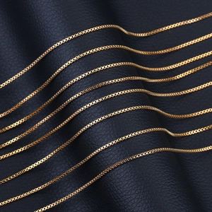 Macro view of gold stainless steel box chains on a textured black leather background