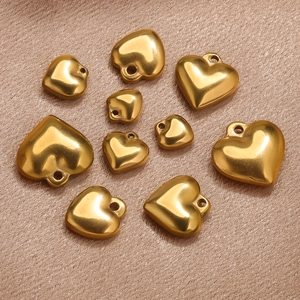 Macro shot of gold-plated stainless steel heart charms in various sizes on satin