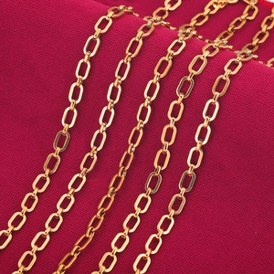 Gouden roestvrijstalen ovale schakelketting voor sieraden op donkerrode getextureerde stof