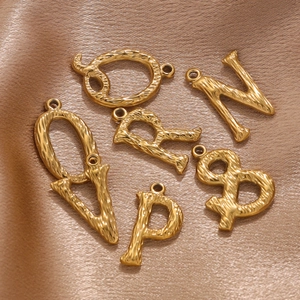 Golden stainless steel alphabet pendants with hammered texture on elegant satin background