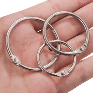 Three sizes of silver stainless steel loose-leaf binder rings held in a hand for scale