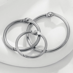 Detailed view of silver stainless steel binder rings in three nested sizes on white pedestal