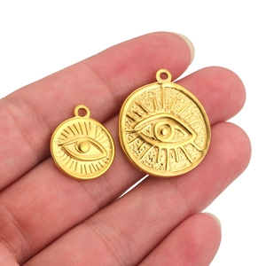 Golden stainless steel evil eye pendant with embossed sunburst texture shown on hand