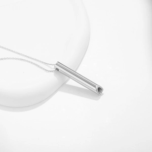 Collar con silbato de respiración de acero inoxidable plateado en soporte de exhibición blanco