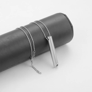 Detalle del colgante de silbato para meditación en acero sobre un soporte de cuero
