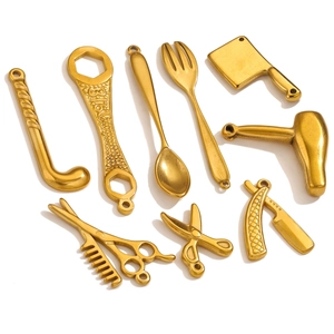 Macro shot of gold stainless steel 316L tool pendants including wrench and scissors