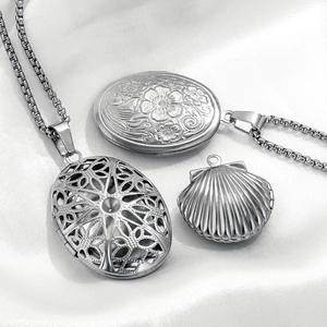 Vintage stainless steel oval locket pendants with floral patterns on white silk