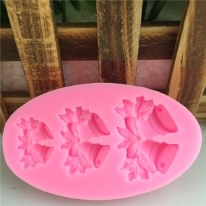 Pink silicone mold featuring three sizes of Christmas bell and holly leaf designs for cake
