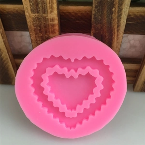Pink heart-shaped silicone mold for fondant cakes and DIY crafts on wood background