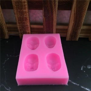 Pink silicone mold featuring four alien face shapes for DIY fondant and resin crafts