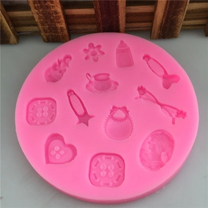 Pink silicone mold for fondant cakes featuring buttons, bottles, and floral designs