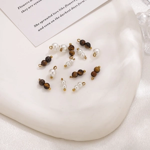 Accesorios para joyas con perlas y piedras ojo de tigre en un plato de cerámica elegante