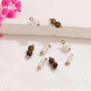 Vista macro de colgantes DIY de perlas y ojo de tigre con aros de acero dorado