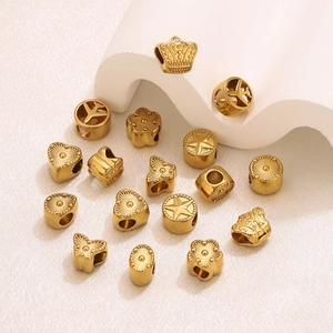 Dettaglio di perline a quadrifoglio e cuore placcate oro 18K per creazione gioielli fai da te