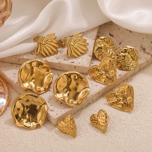 Polished gold stainless steel heart and geometric drop earrings on elegant silk fabric