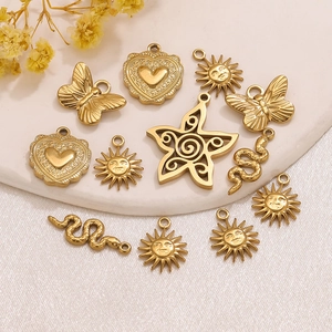 Macro view of gold-plated stainless steel charms including sun, snake, heart and butterfly