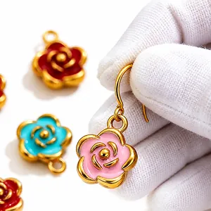Macro view of colorful stainless steel camellia pendants held by a gloved hand