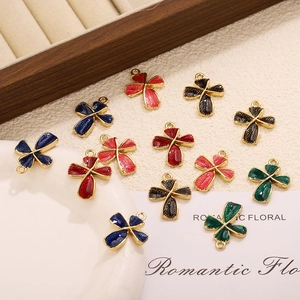 Vue macro de pendentifs croix en émail coloré avec bordure dorée sur colliers minimalistes