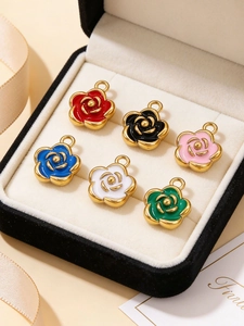 Detail of six colorful enamel camellia rose charms in a premium black velvet jewelry box