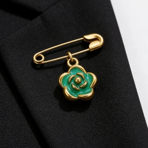 Golden safety pin brooch with green enamel camellia pendant on black suit lapel