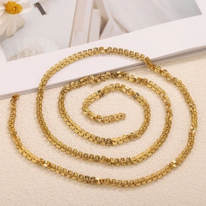 Close-up of golden fan-shaped links with fine radial texture on a luxury chain necklace