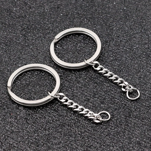 Macro detail of two silver stainless steel keyrings with curb chains on black surface