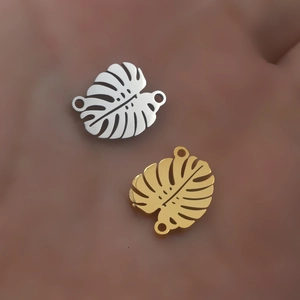 Macro detail of leaf-shaped jewelry connectors in gold and silver stainless steel