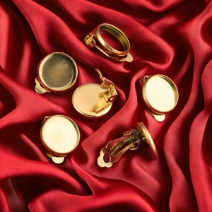 Golden round stainless steel clip-on earring bases for DIY jewelry on red silk