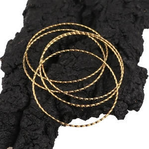 Set mit 5 goldenen Armreifen aus Edelstahl mit gedrehtem Muster auf schwarzem Grund