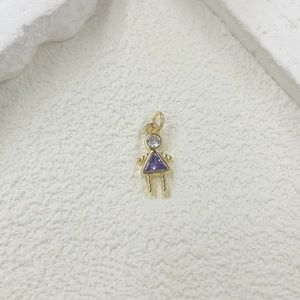 Macro detail of a gold girl charm with clear zircon head and purple triangle stone