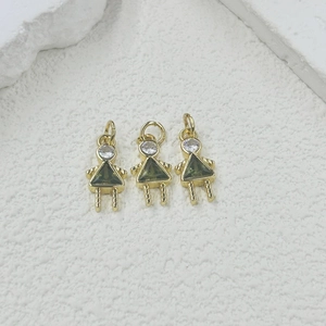 Close-up of golden girl-shaped pendants with green triangle stones for DIY jewelry