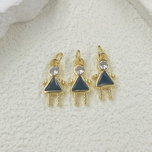 Detailed view of three gold girl pendants with black triangular skirts and zircon stones