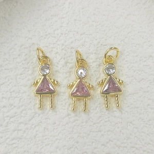 Macro shot of three gold-plated girl-shaped pendants with pink triangular zirconia stones