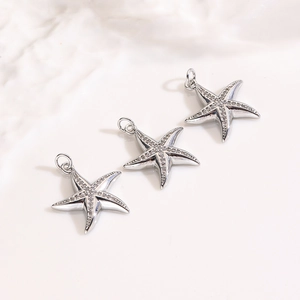 Vista macro di tre ciondoli a forma di stella marina in finitura argento con micro-zirconi
