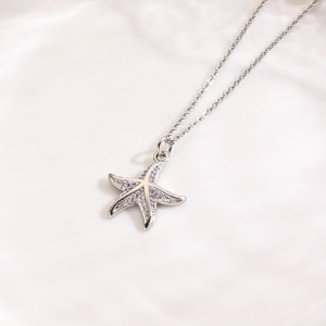 Dettaglio macro di una collana con ciondolo a stella marina in argento e zirconi bianchi