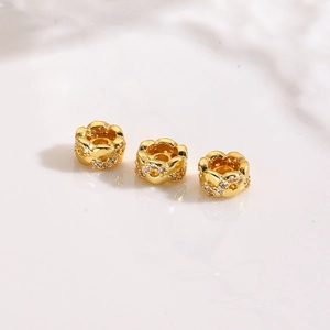 Detailed macro view of 18K gold-plated spacer beads with hollow petal design and zircon