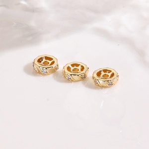 Detailed macro view of 18K gold-plated spacer beads with inlaid clear cubic zirconia
