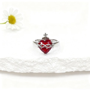 Détail macro d'une bague couronne en argent avec zircon rouge sur fond de pierre blanche