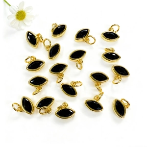 Dettaglio macro di ciondoli placcati oro a forma di occhio con pietra nera per gioielli DIY