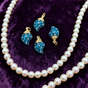 Ciondoli a conchiglia in smalto blu con placcatura in oro e strass su velluto viola