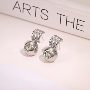 Detailed macro view of minimalist silver earrings with polished metal and clear gemstones