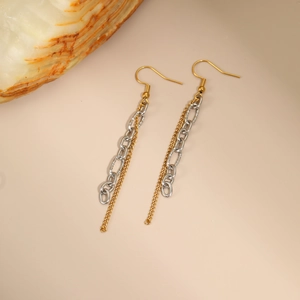 Détail macro de boucles d'oreilles à pompon avec chaîne bicolore en or et argent poli