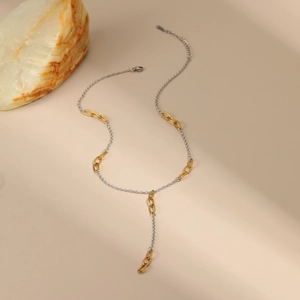 Detail of a dual-tone gold and silver Y-shaped stainless steel necklace with oval links