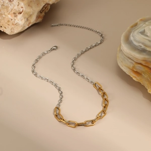 Detailed close-up of mixed gold and silver link chain necklace on a natural stone base