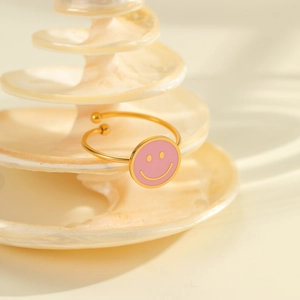 Detailaufnahme eines 18K vergoldeten Rings mit einem rosa Emaille-Smiley-Blumendesign
