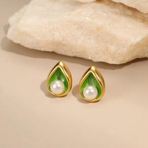 Detailed macro view of gold waterdrop earrings with green enamel and center pearl inlay