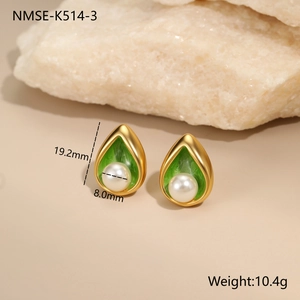 Detail view of 18K gold teardrop earrings with green enamel and white pearl accents