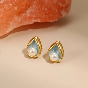 Water drop pearl earrings in 18K gold plated steel with blue enamel and orange stone background