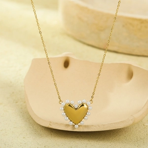 Primer plano del colgante de corazón en oro de 18K con perlas elegantes y cadena dorada